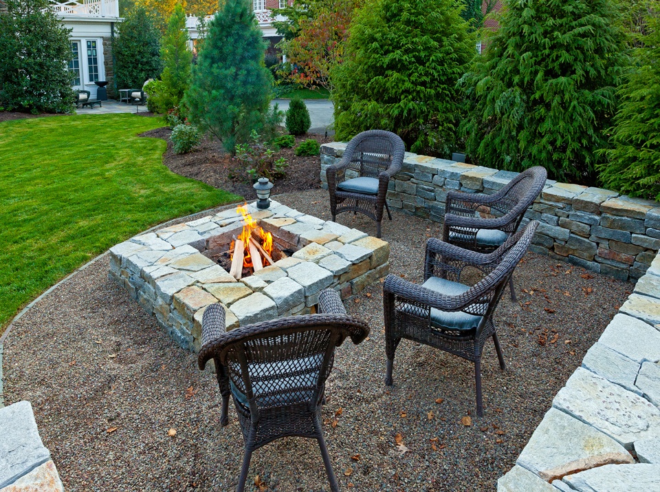 square stone fire pit and wall on gravel
