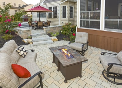 Home patio landscape with fire pit, pavers, and shrubs